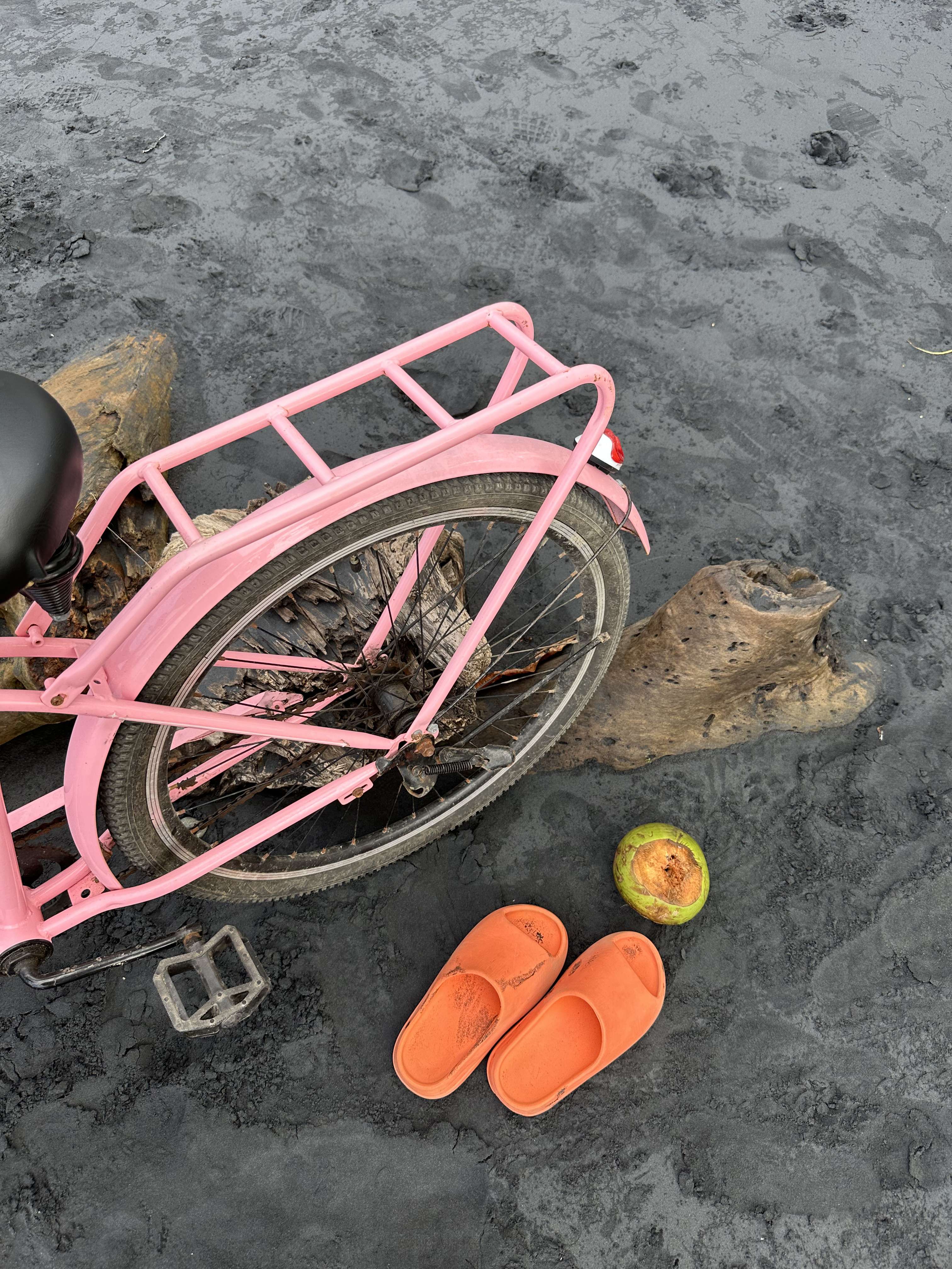 Beach bike, coconut, and Yeezy slides on the black sand of Playa Negra, Puerto Viejo